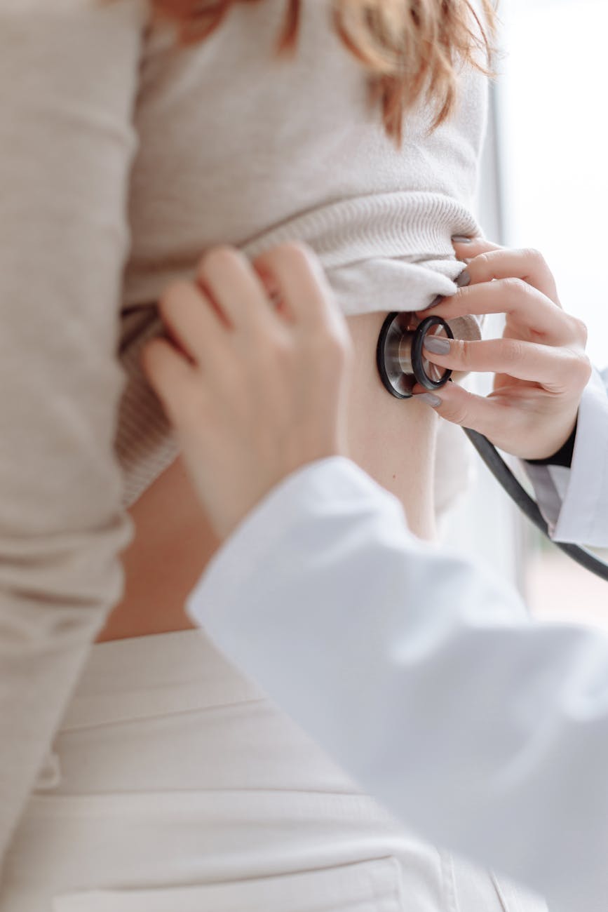 a person in white long sleeves checking up the back of the patient using stethoscope