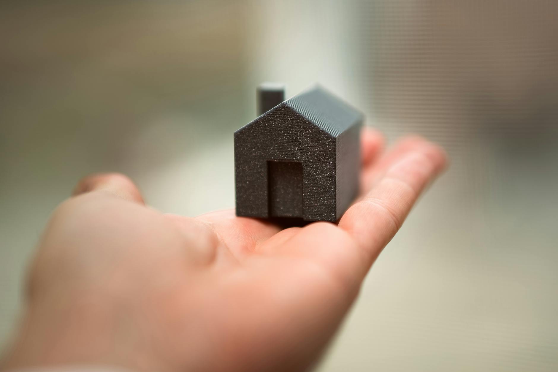 hand holding small model house symbolizing real estate