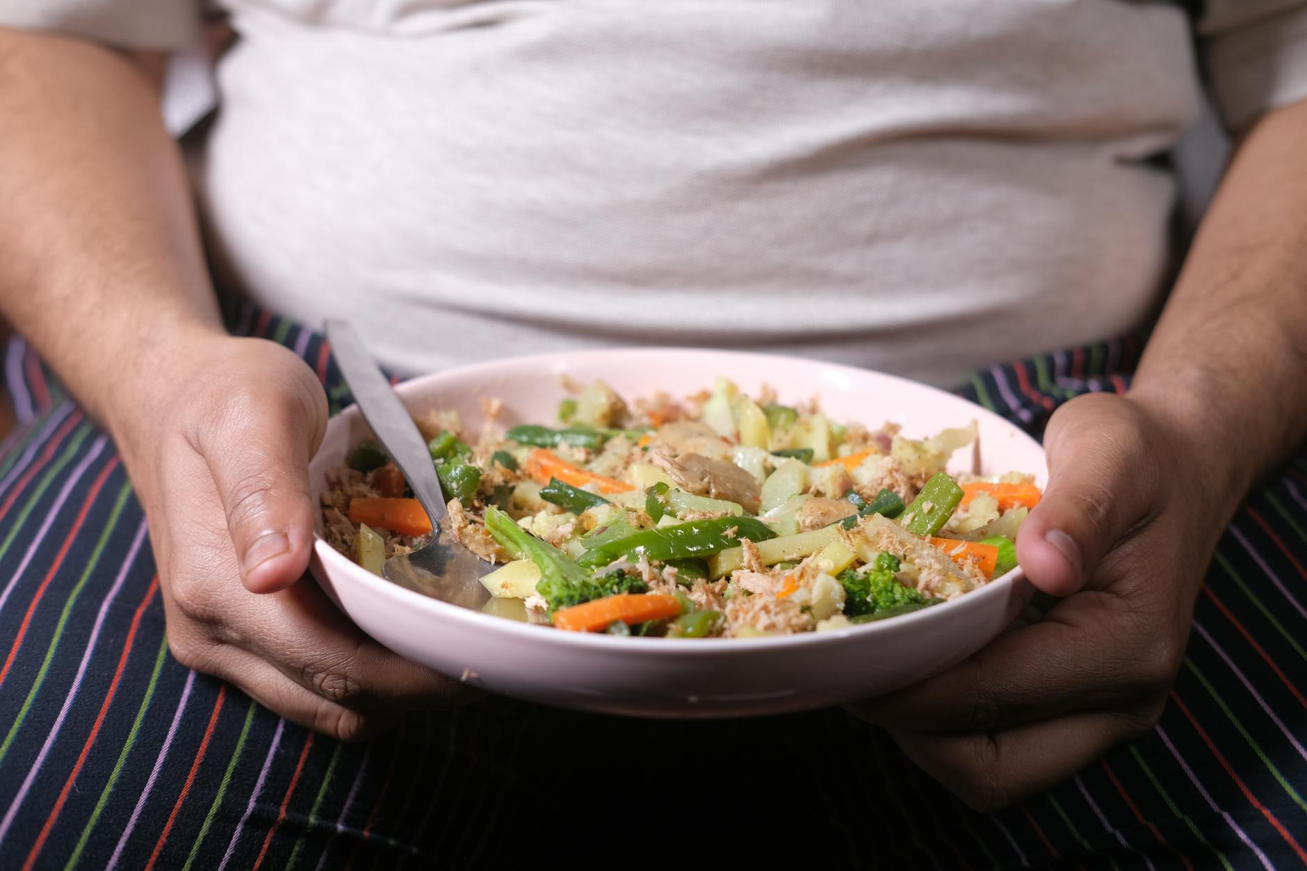 person holding a plate of cooked vegetables